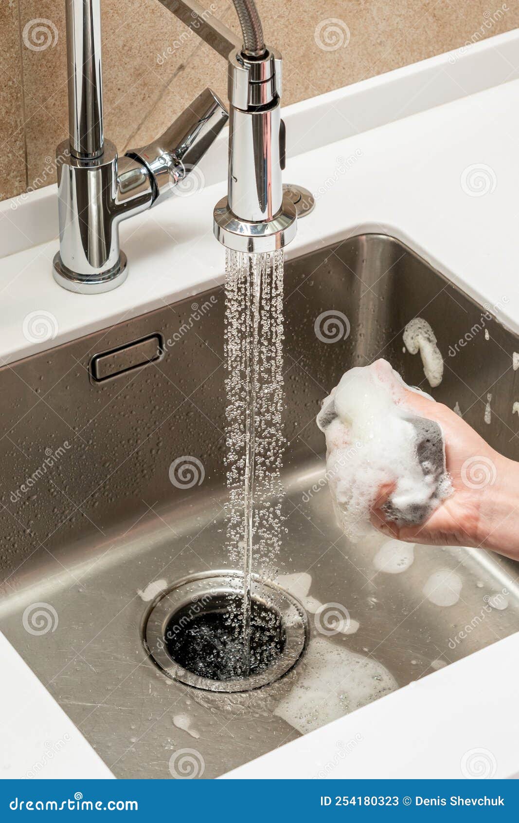 Sponge with Cleaning Agent in Female Hand Over Kitchen Sink Stock Image