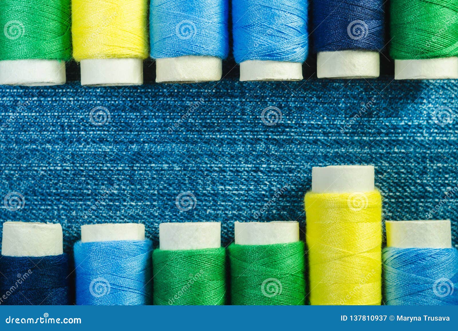 Spools of Blue, Yellow and Green Sewing Thread Arranged in Two Rows on