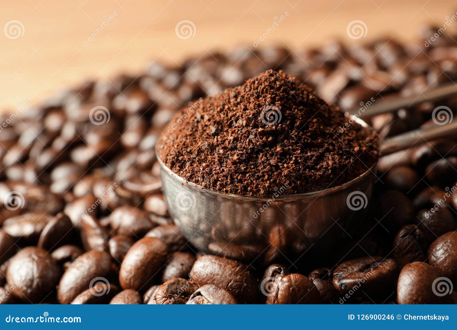 spoon with coffee grounds and roasted beans on table