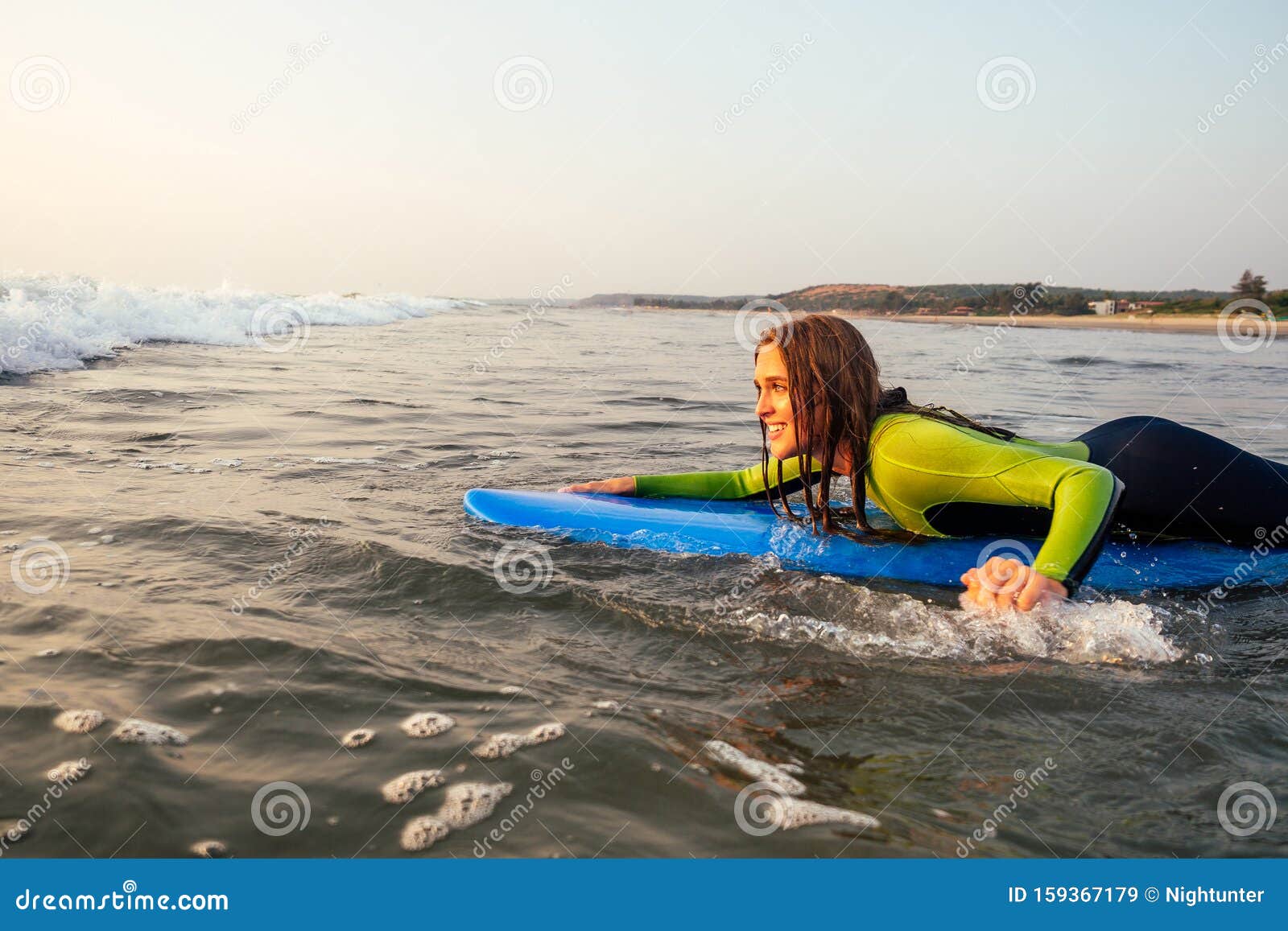 Sporteert Een Mooie Vrouw in Een Duikpak Dat Op Een Surfbord Ligt Te Wachten Op Een Grote Golf Surf in Een Waterpak Dat Bi Stock Afbeelding - of bali: