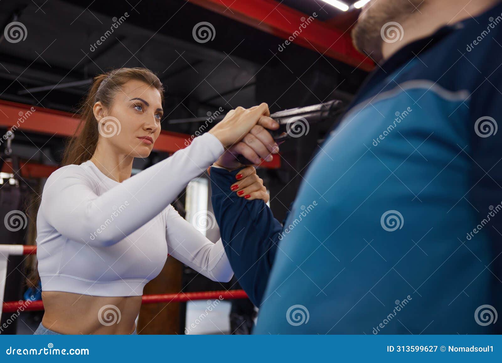 sportive young woman training self-defense from attacker with gun weapon