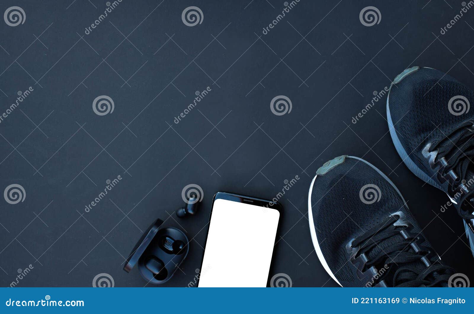 sports shoes with smartphone and headphones on black background