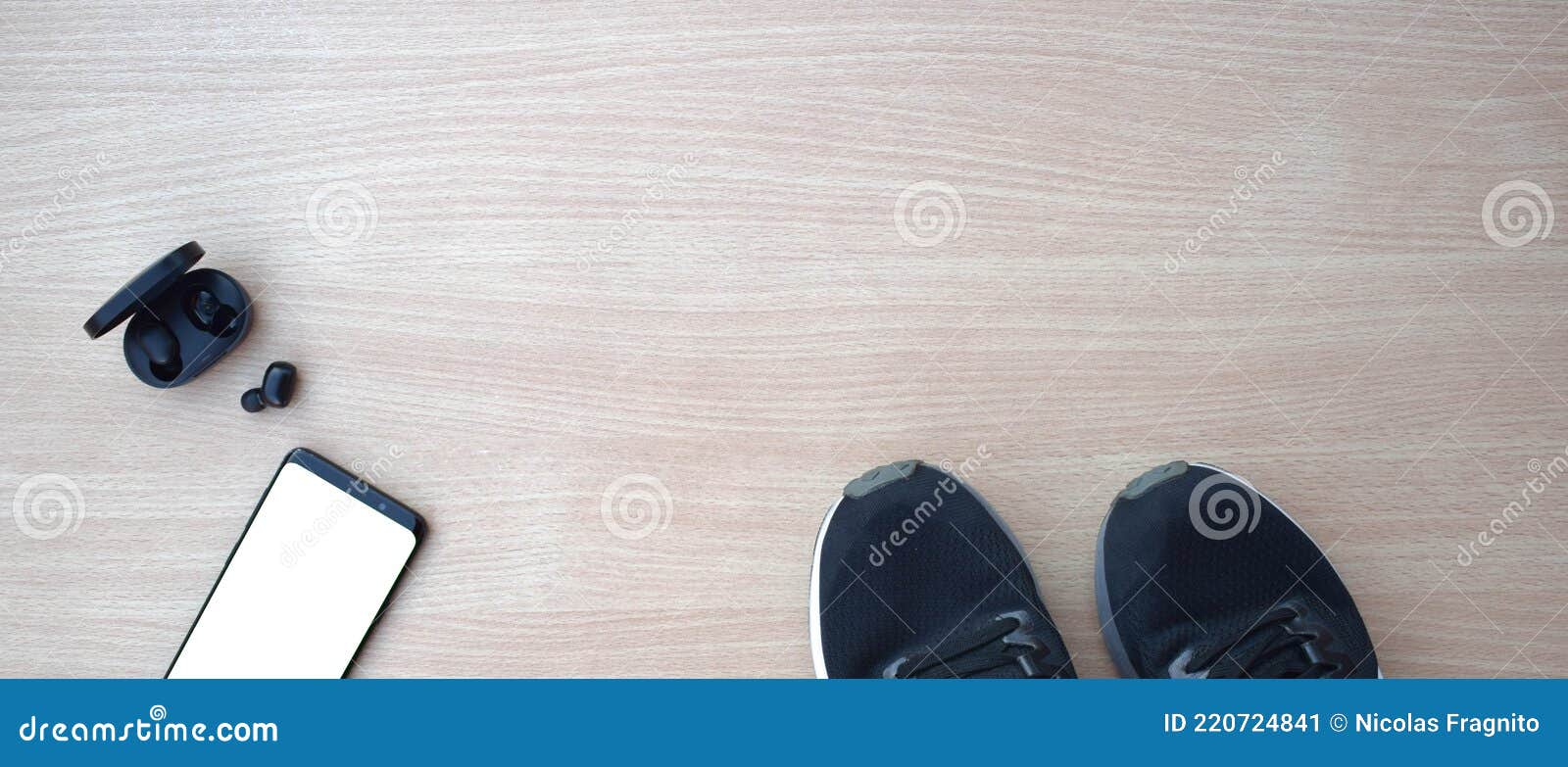 sports shoes with smartphone and headphones on wooden table