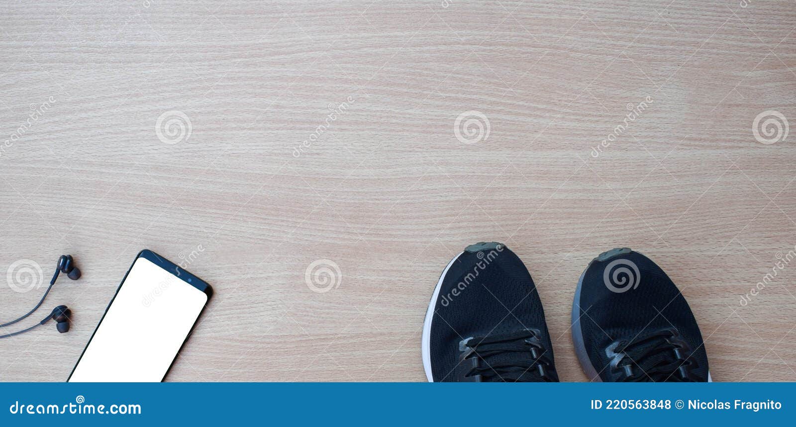 sports shoes with smartphone and headphones on wooden table