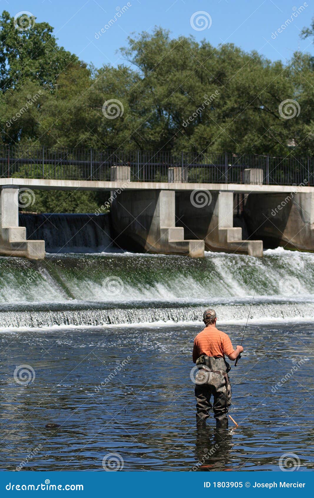 sportsman in waders fishing at dam