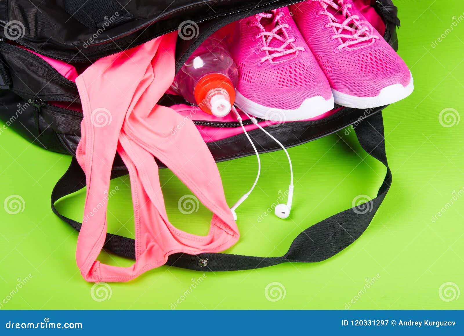 Sportswear e acessórios cor-de-rosa para a aptidão, em um saco em uma luz - fundo verde