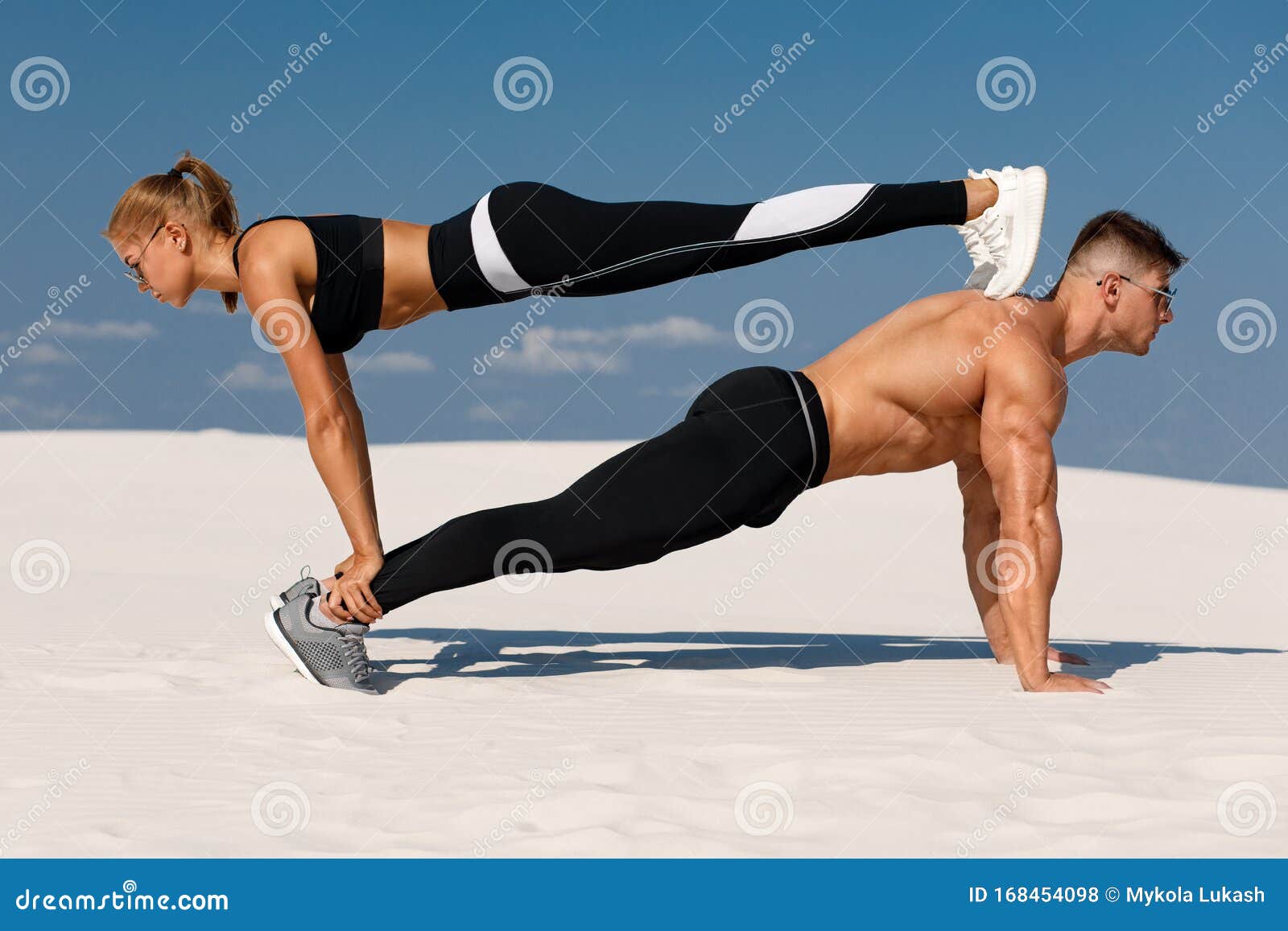 sporty fitness couple doing planking exercise outdoors. beautiful athletic man and woman workout
