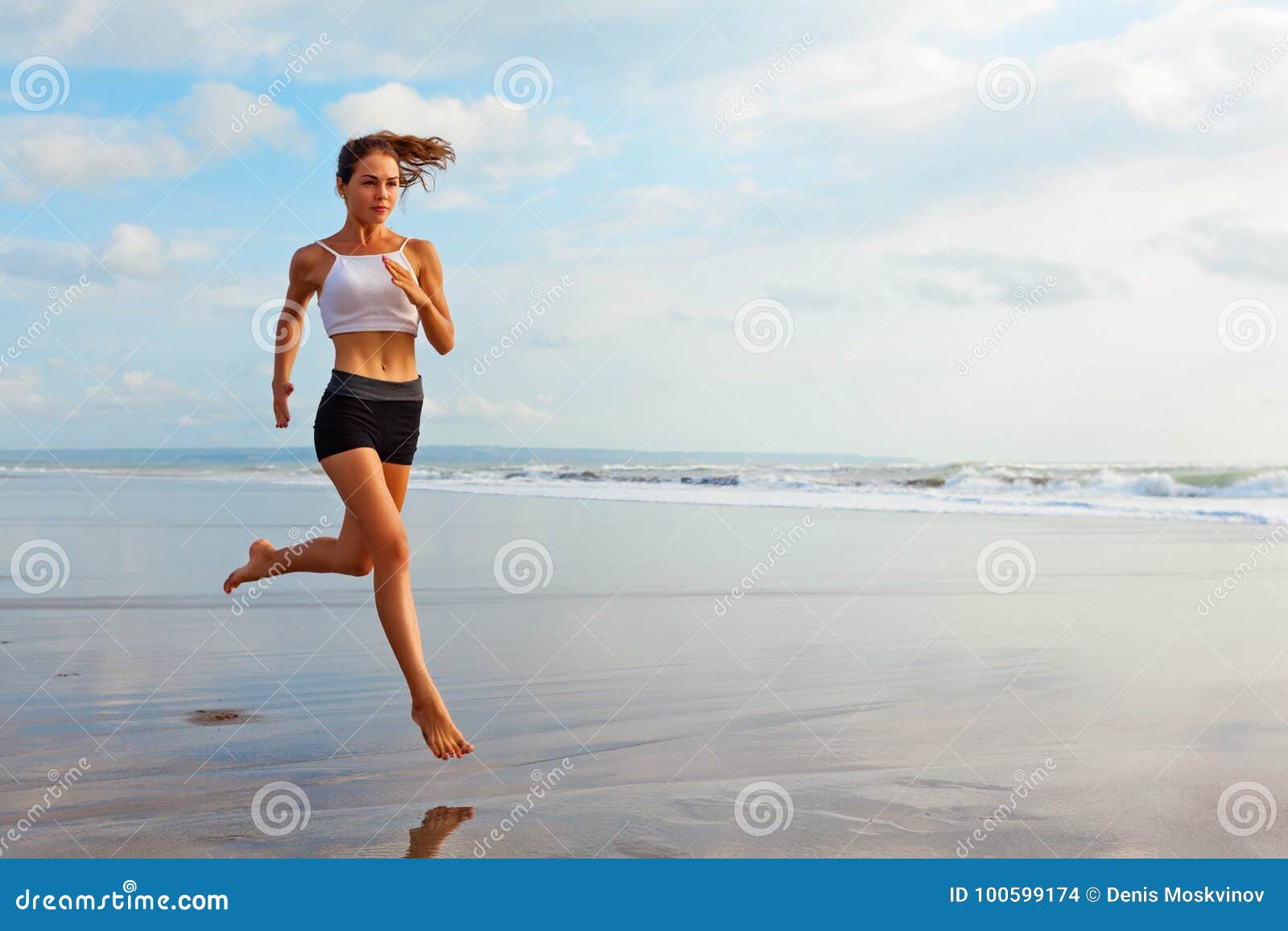 sporty girl running by beach along sea surf