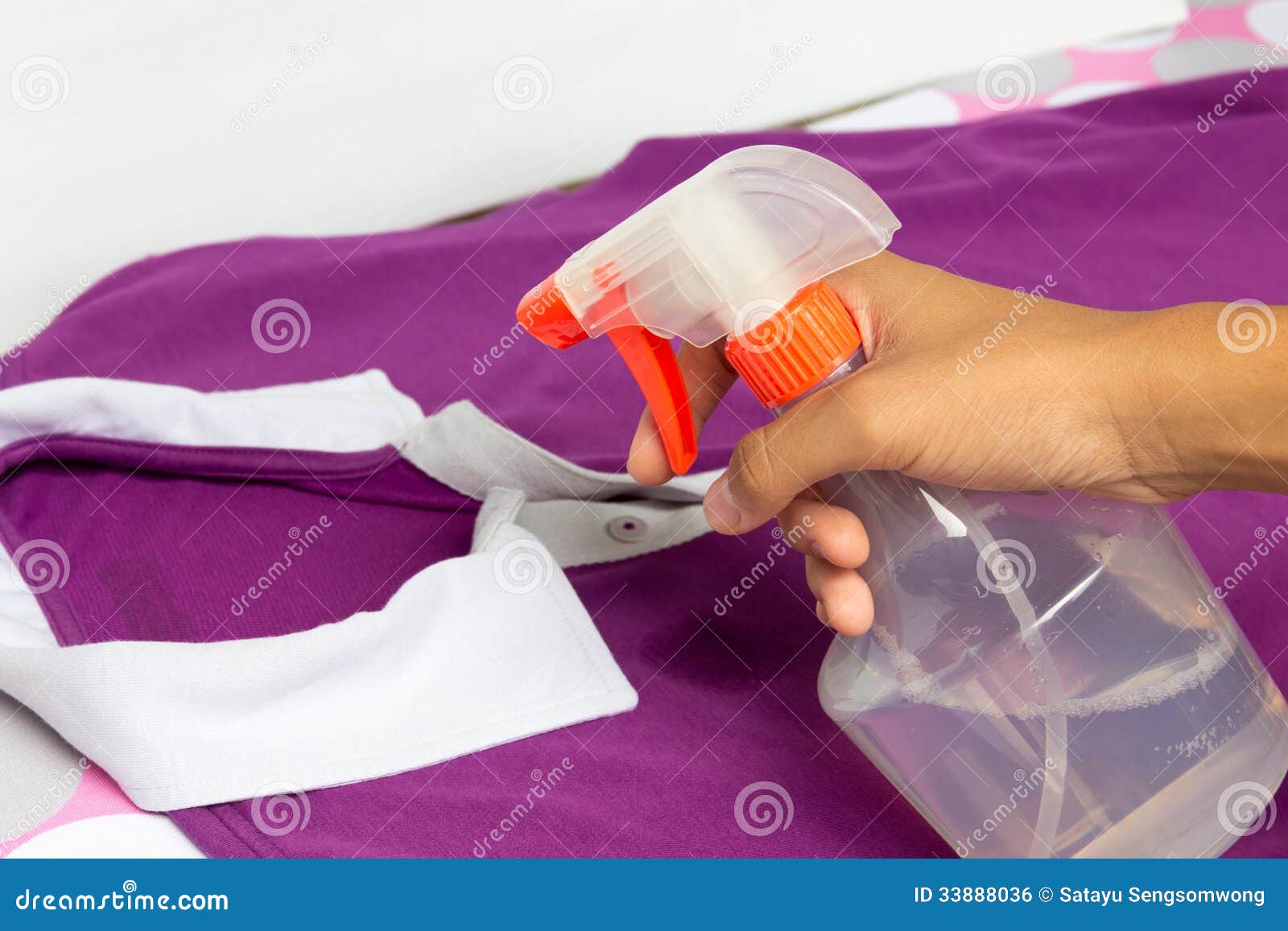 spraying a casual cloth with laundry detergent in spray bottle