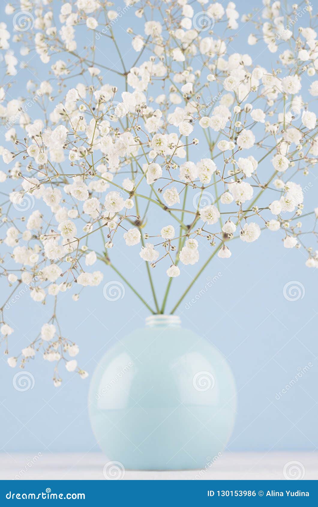 Spring Branch With Small White Flowers In Blue Sphere Vase spring branch small white flowers blue sphere vase soft light modern wall table closeup