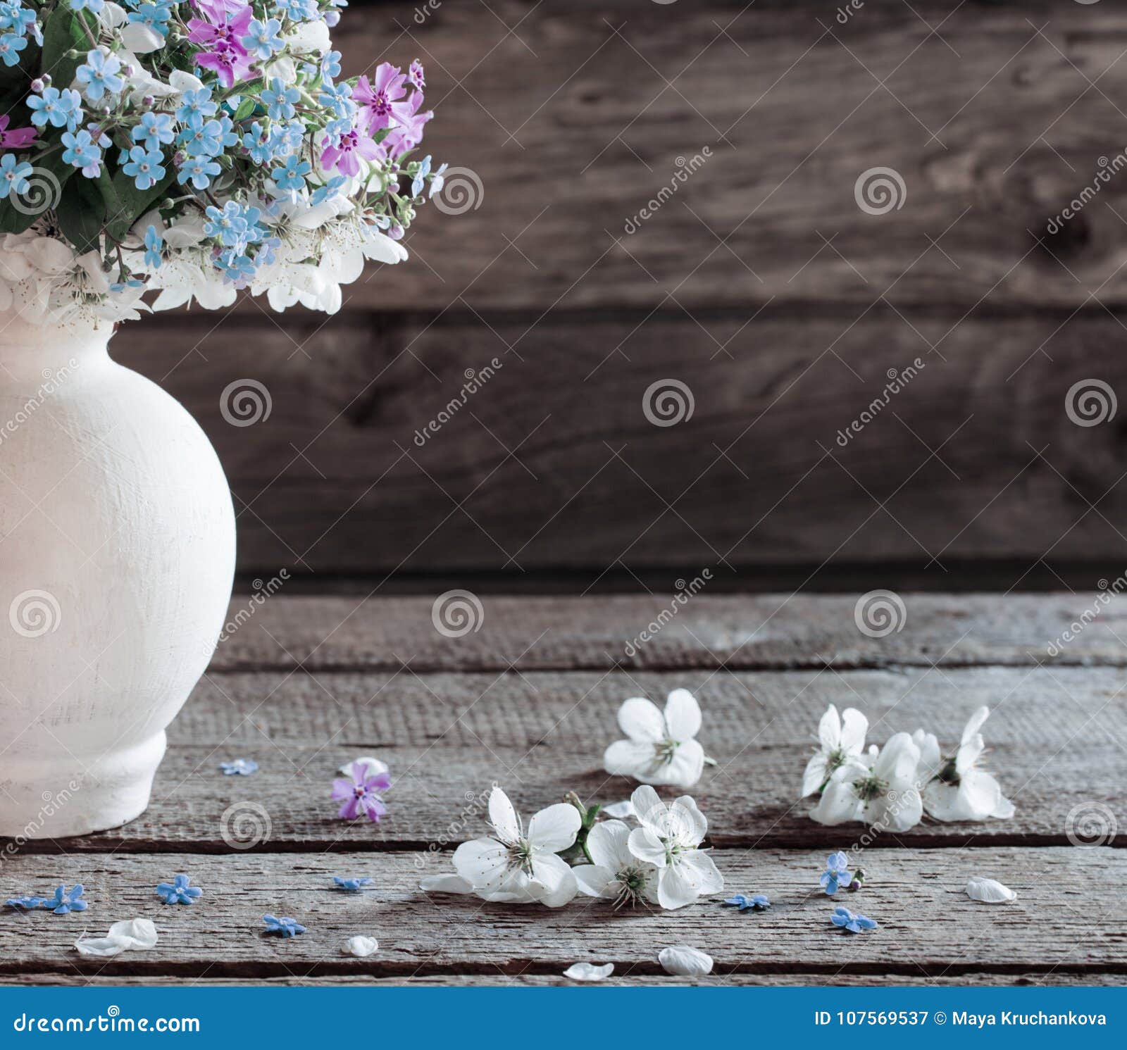 The spring flowers in vase on dark wooden background