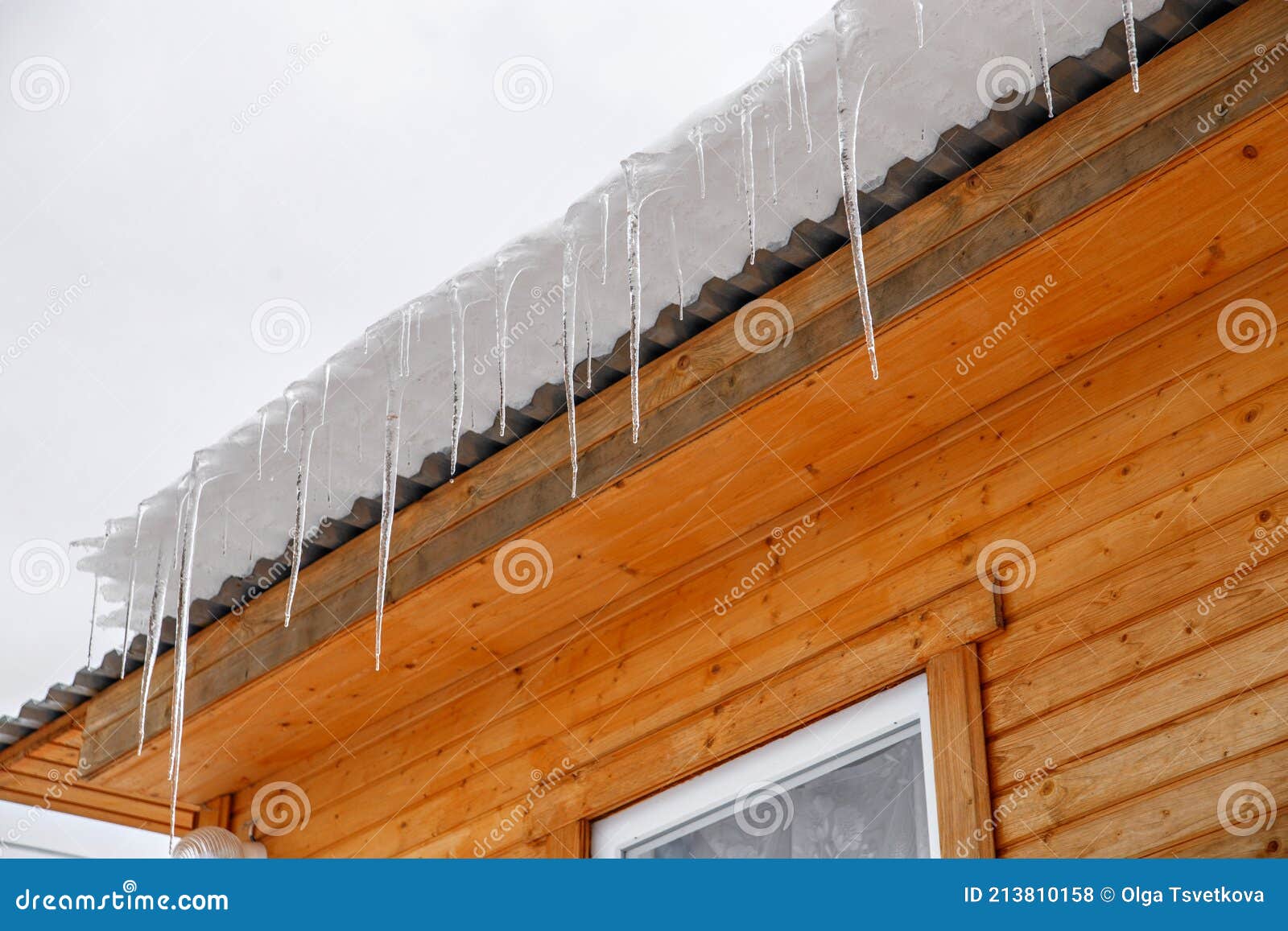 Spring Ice Icicles on Roof of House. Patterns Scattered by Sun and