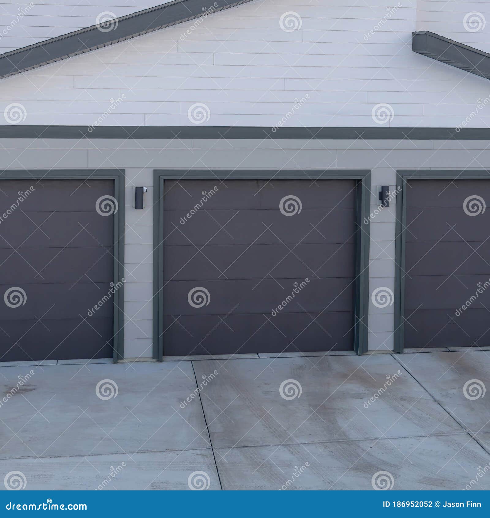 square frame three door garage of a lovely home against snowy slope and cloudy blue sky
