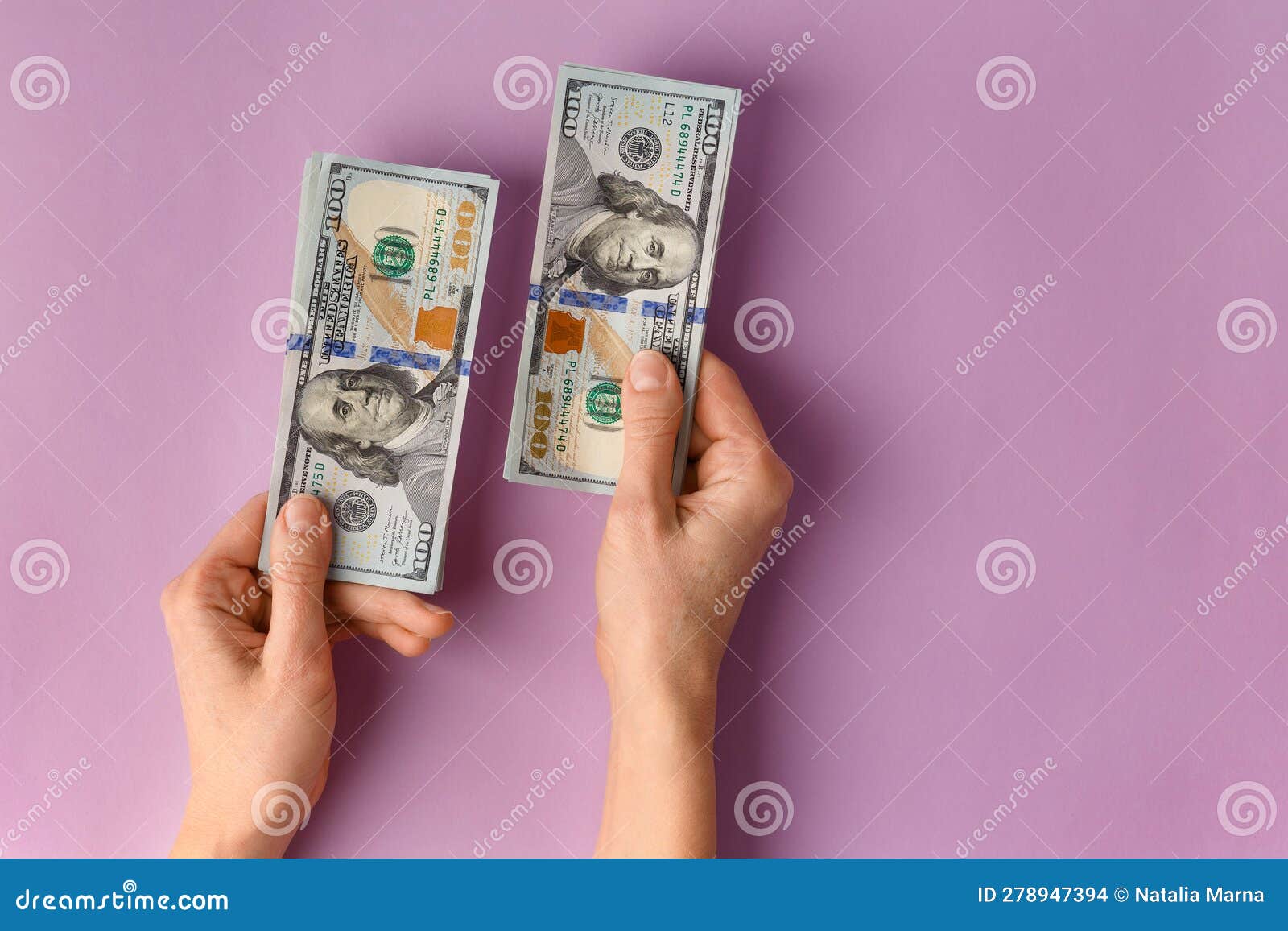 A Stack Of Banknotes Of 100 Dollars In Female Hands On A Pink a-stack-of-banknotes-of-100-dollars-in-female-hands-on-a-pink