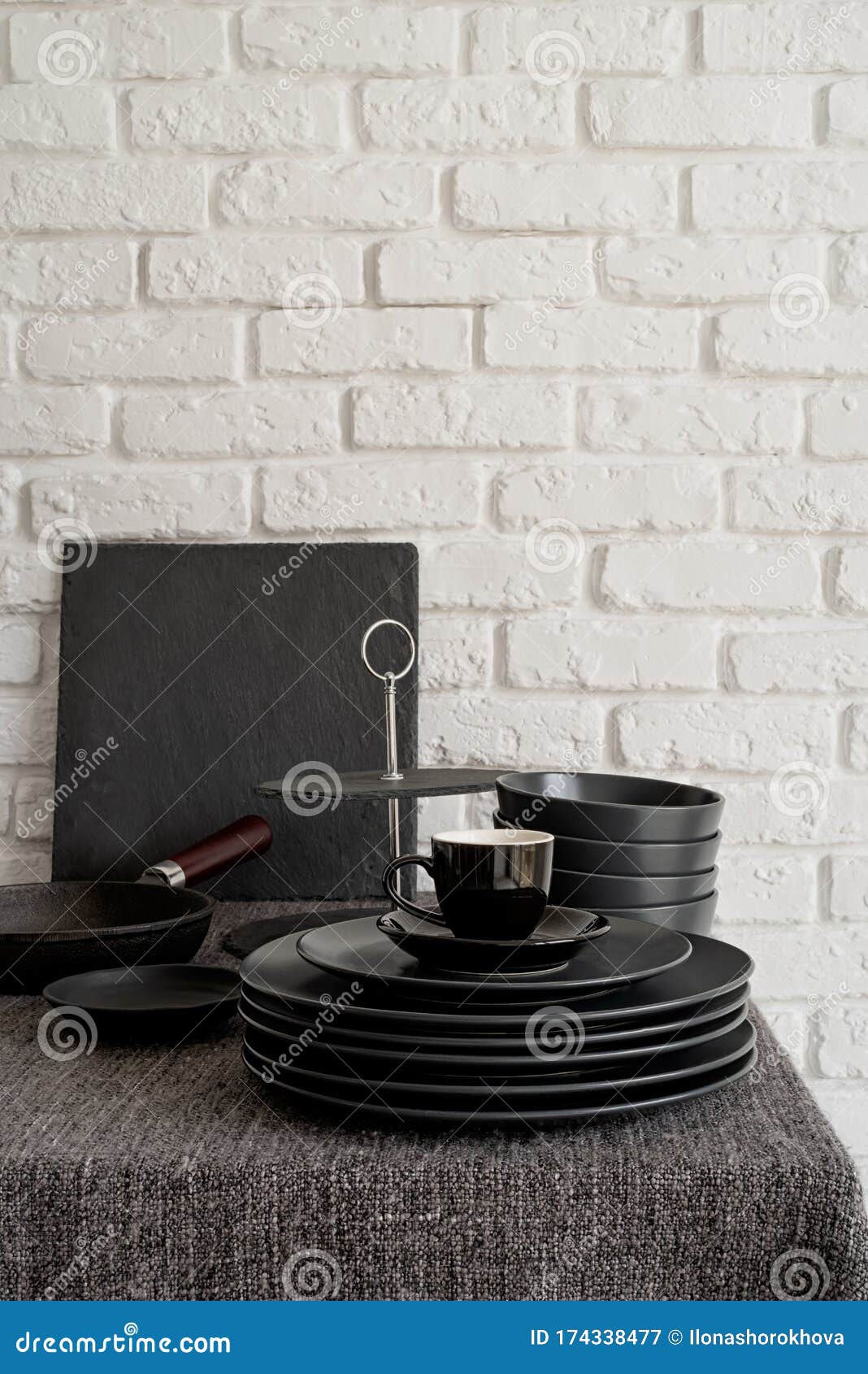 Stack of Black Ceramic Dishes and Tableware on the Table on White Brick