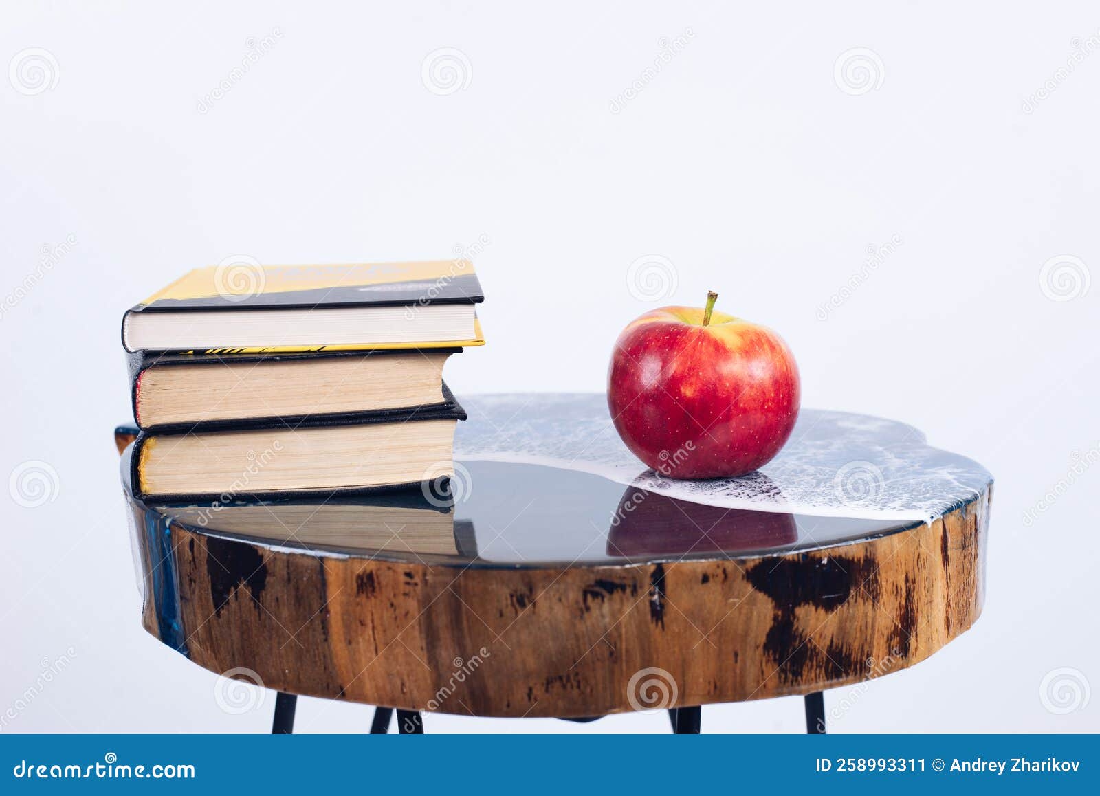 A Stack of Books. a Book and an Apple on the Table. Table Made of Epoxy