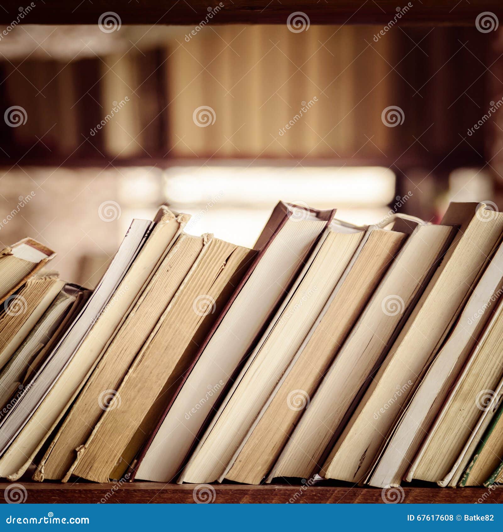 Stack of books on library bookshelf against blurry background - Square 