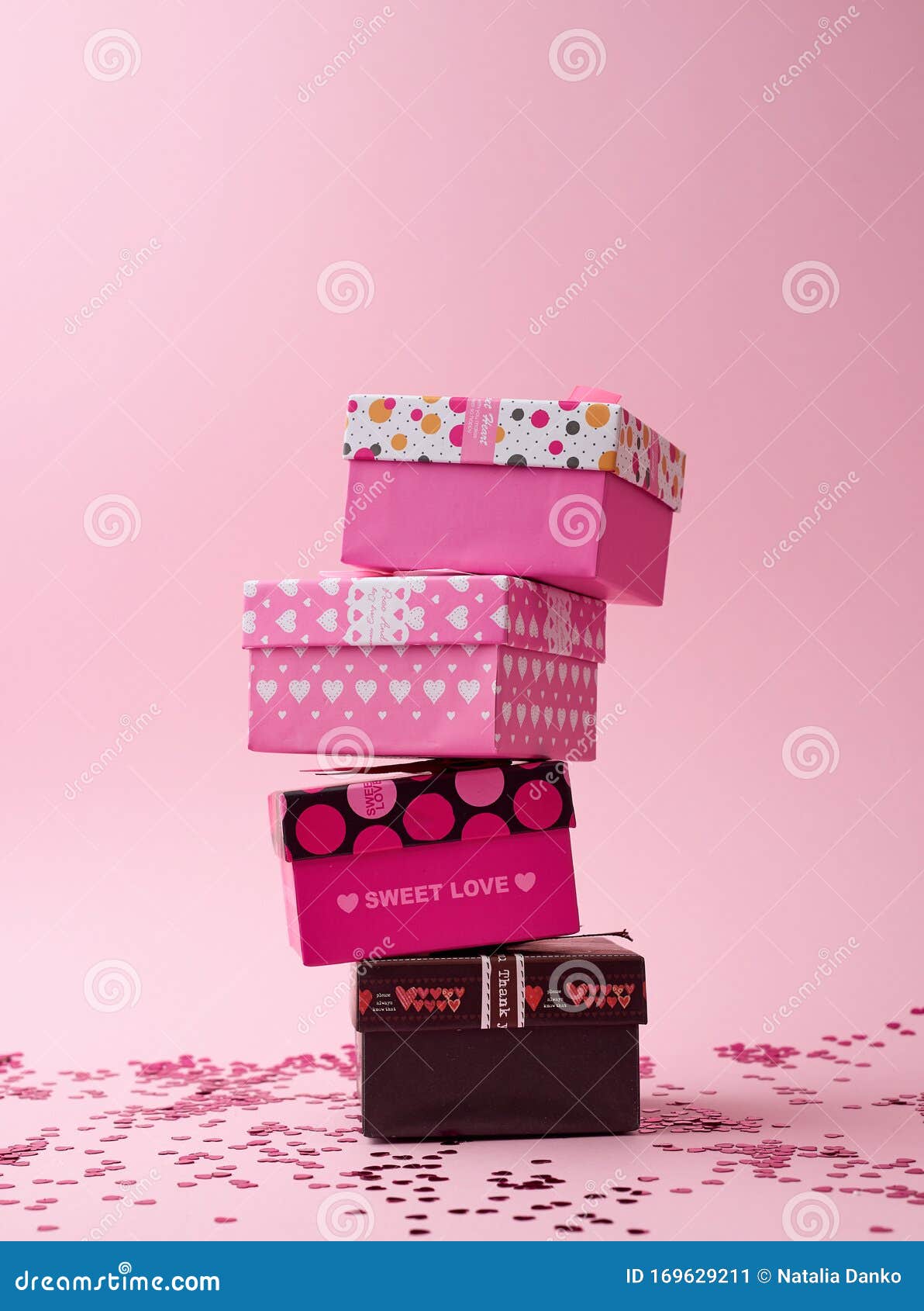 Stack of Cardboard Square Gift Boxes on a Pink Background with Shiny