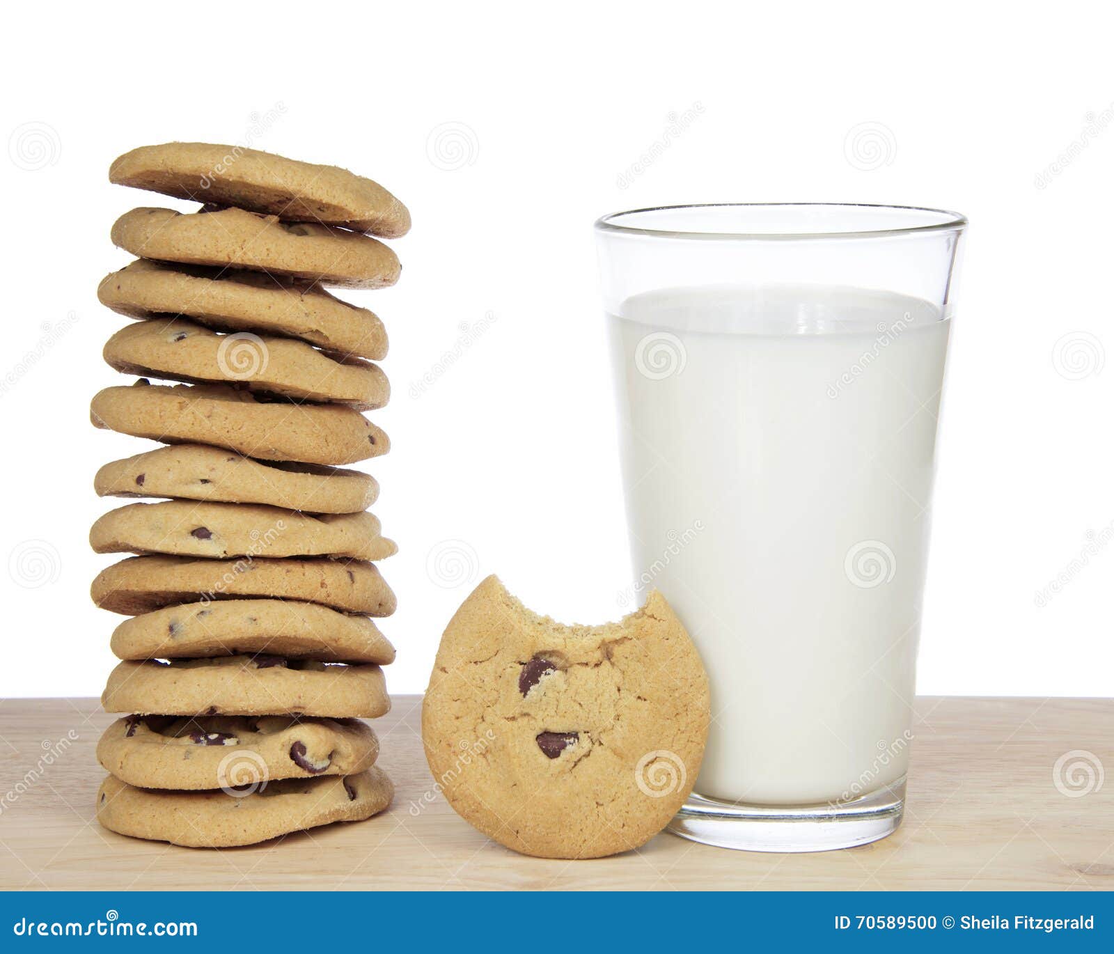 Stack of 12 chocolate chip cookies next to a glass of milk with one cookie with bite missing standing up next to glass