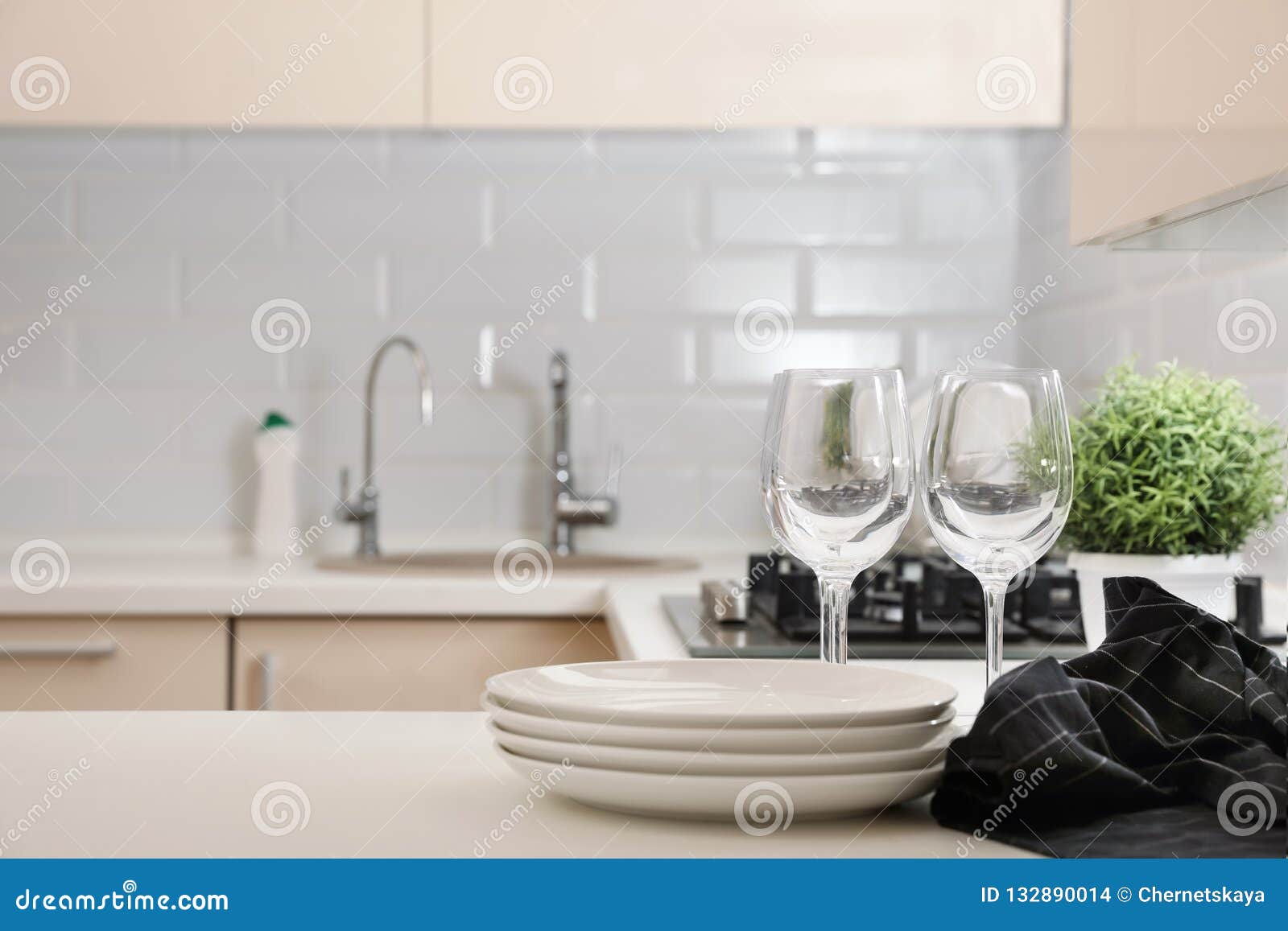 Stack of Clean Dishes and Glasses on Table in Kitchen. Stock Photo