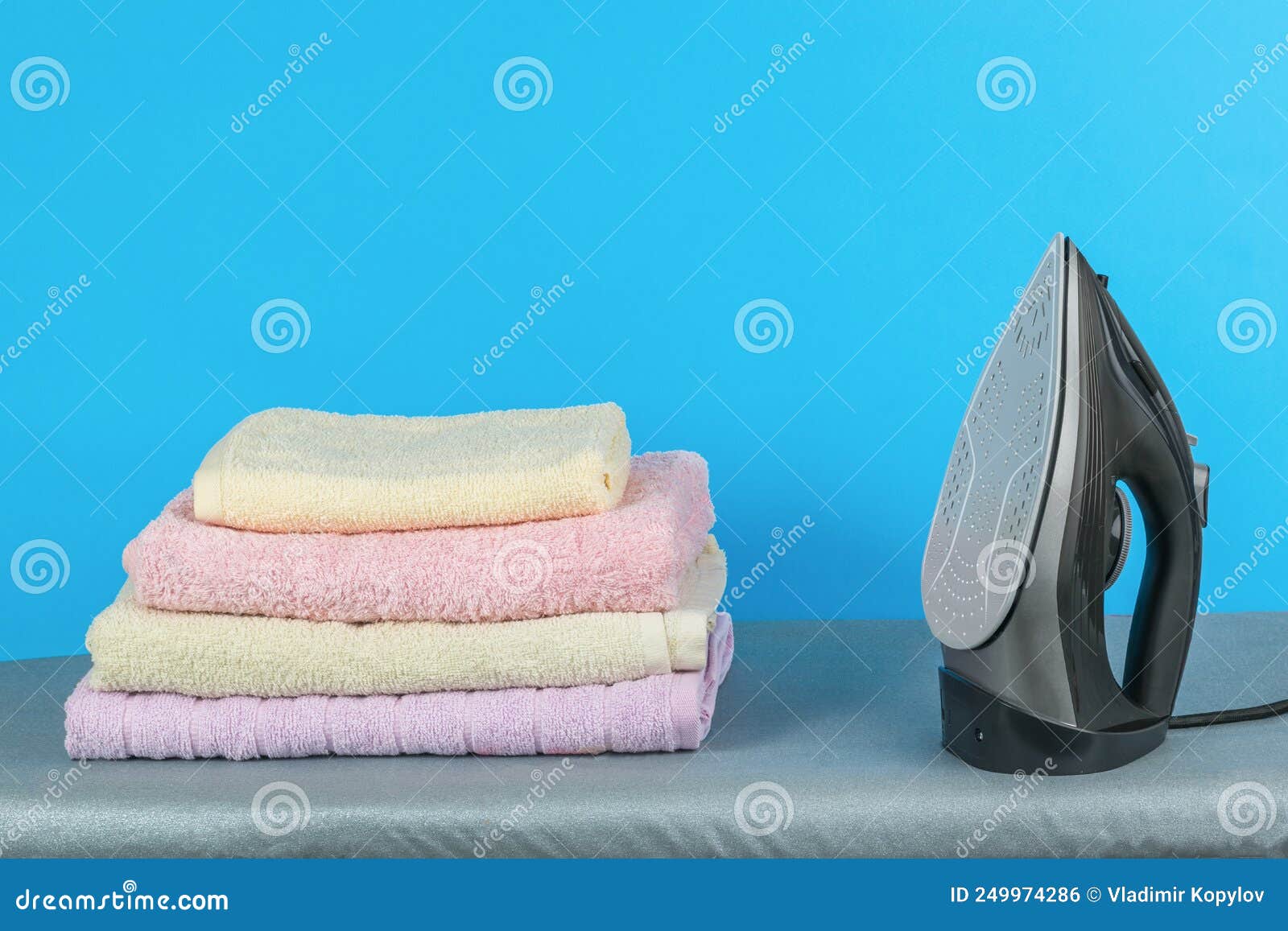 A Stack of Clean Ironed Linen and an Iron on the Ironing Board Stock