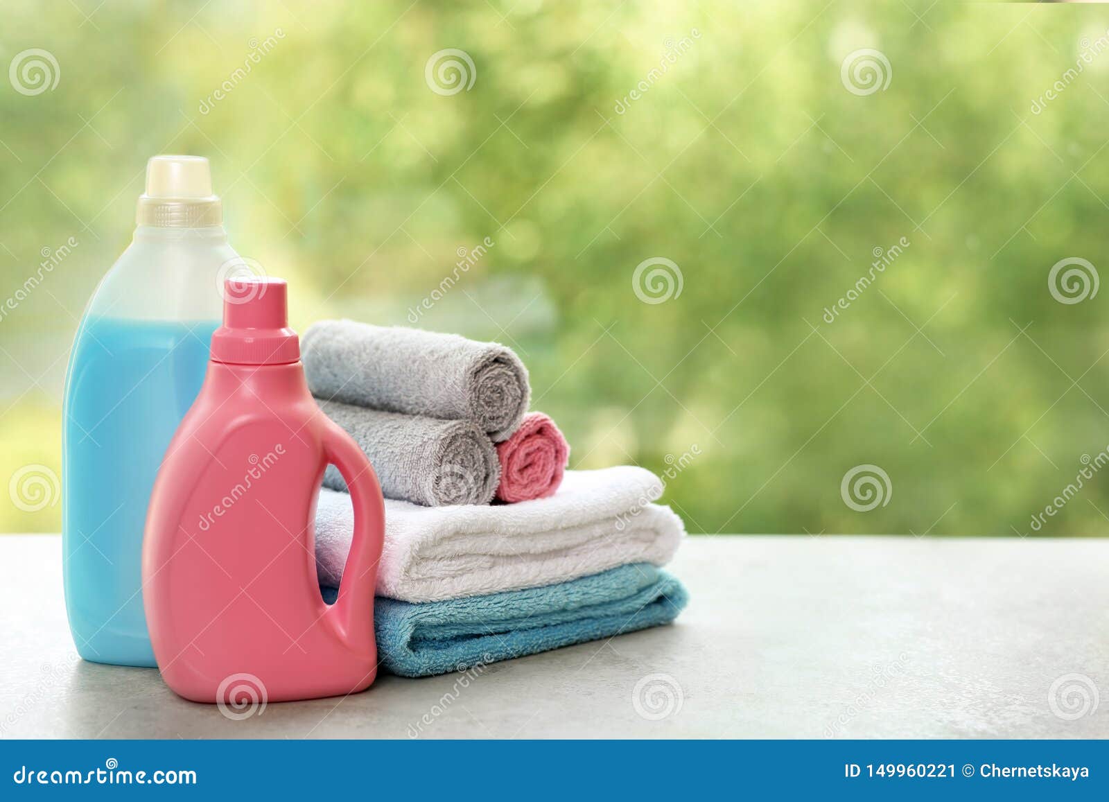 Stack of Clean Towels with Detergents on Table Against Blurred