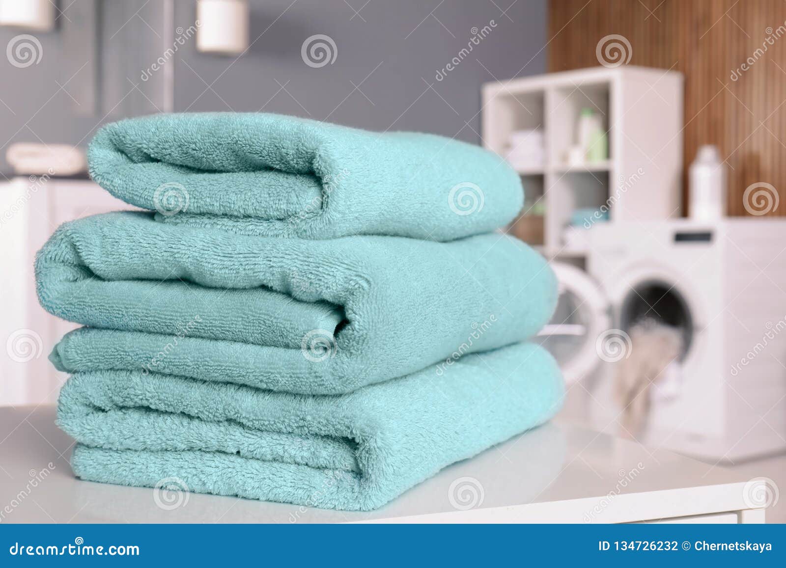 Stack of Clean Towels on Table in Laundry Room. Stock Photo Image of