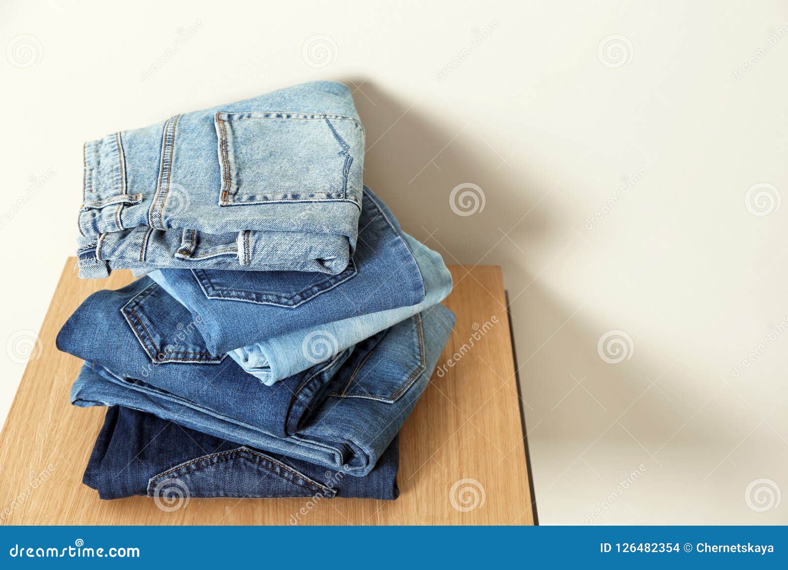 Stack of Different Jeans on Table Against Light Background Stock Photo ...