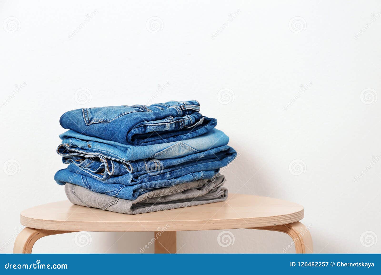 Stack of Different Jeans on Table Against White Background Stock Image