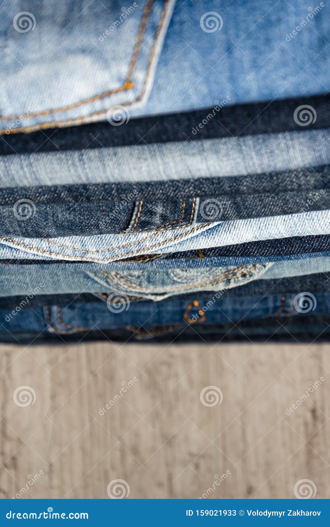 A Stack of Folded Jeans on Wooden Background. Close-up of Jeans in ...