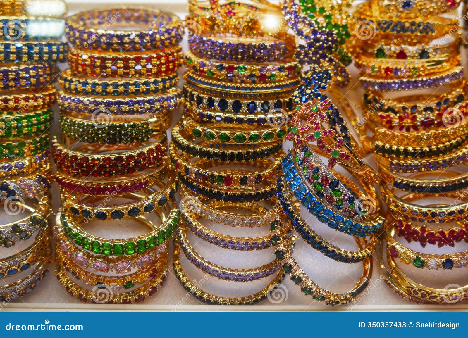 stack of golden bracelets with colorful crystals for sale in cambodia, siem reap market