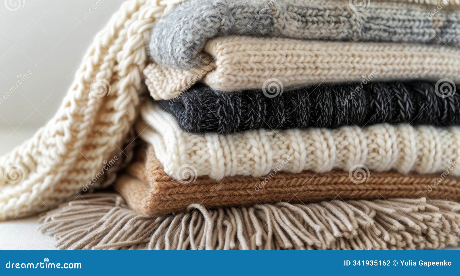 stack of knit blankets with fringes on a couch
