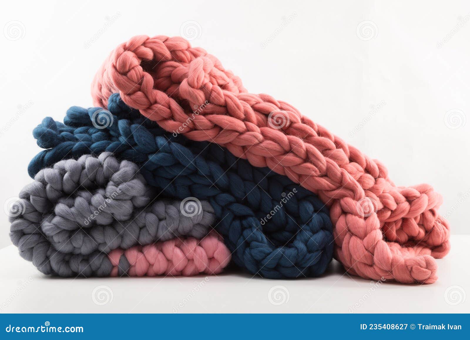 A Stack of Knitted Blankets from Natural Materials on a White