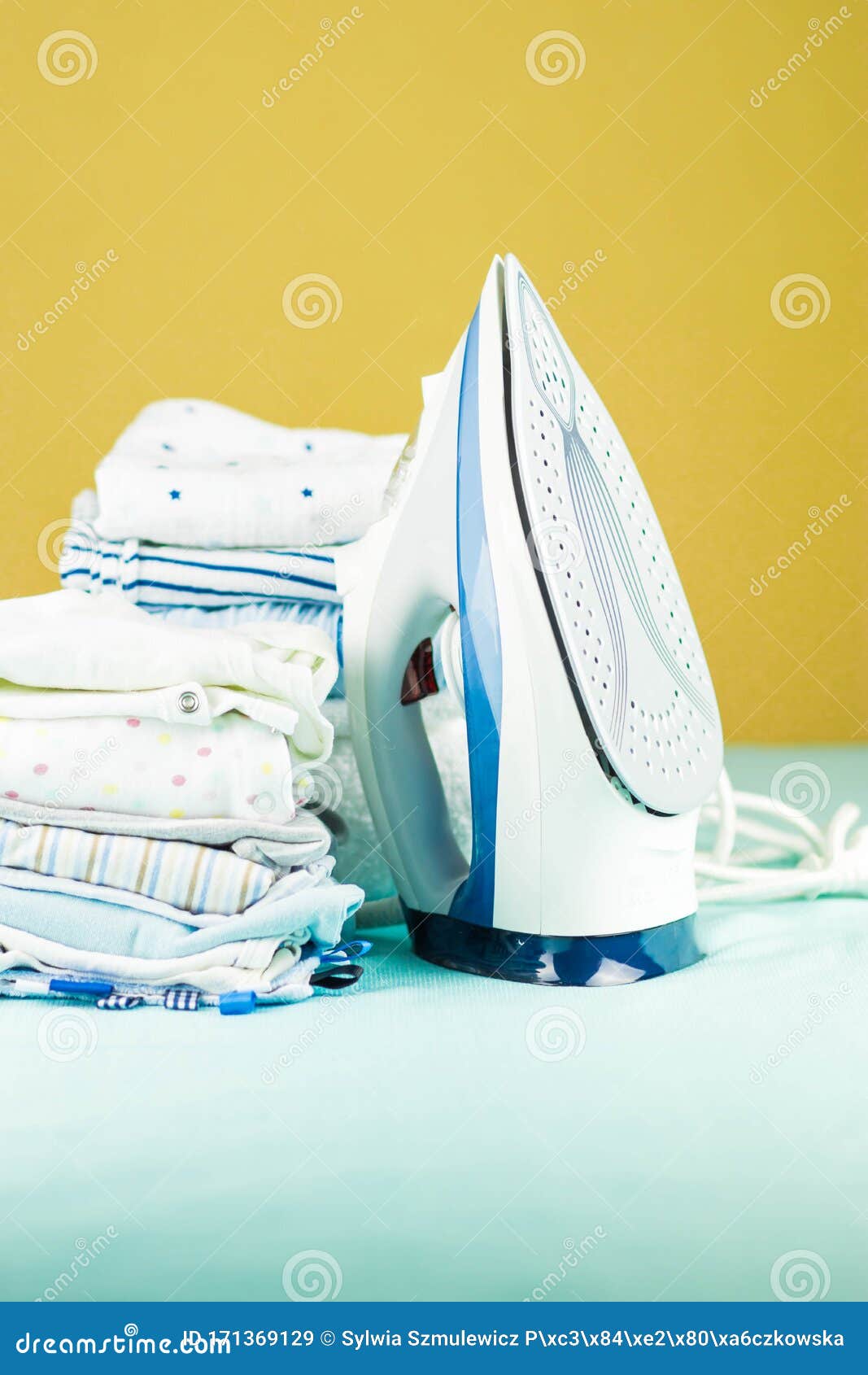 Stack of Newborn Baby Clothes Pressed with an Electric Iron Stock Image