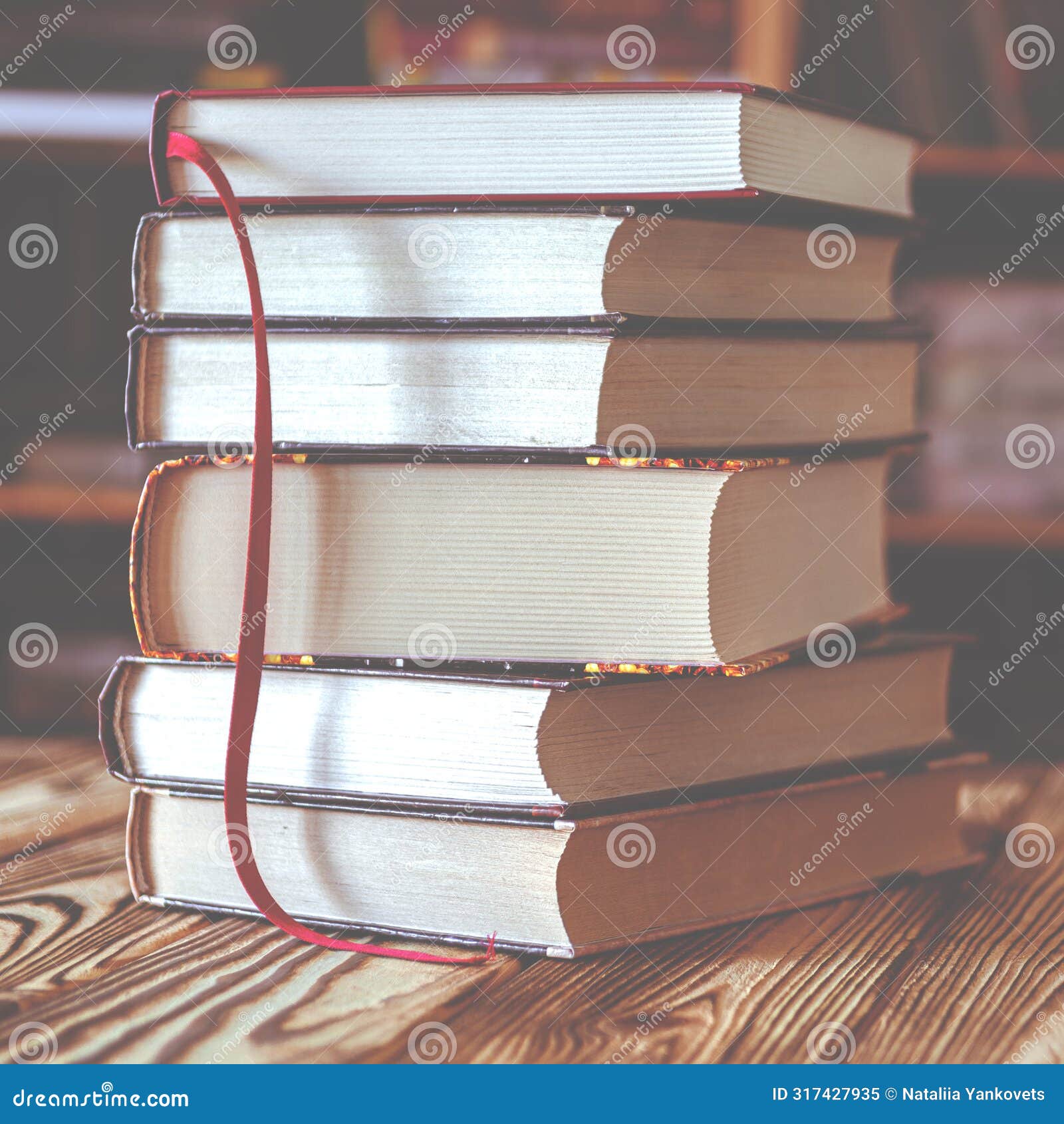 a stack of old books on table against background of bookshelf in library. conceptual background on education, literature