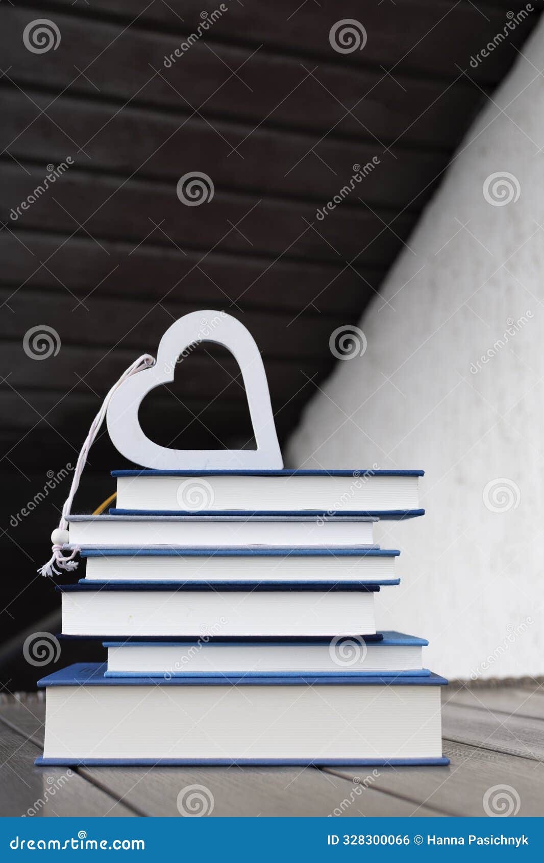 stack of several books and a heart on top of them on a table on a light and dark background