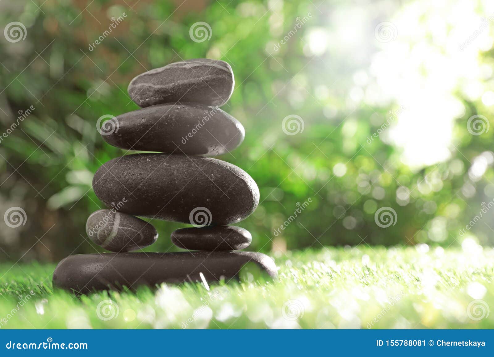 Stack of Stones on Green Against Blurred Background, Space for Text