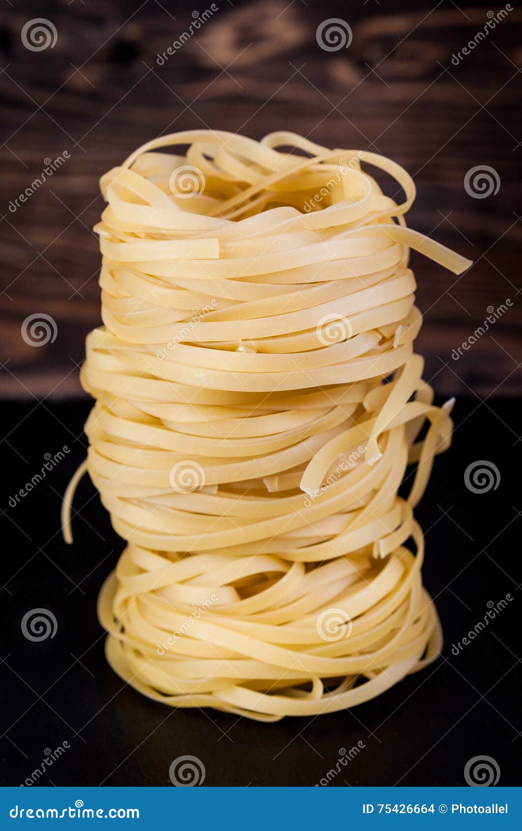 Stack of Tagliatelle Pasta Nests Over Dark Wooden Background Stock