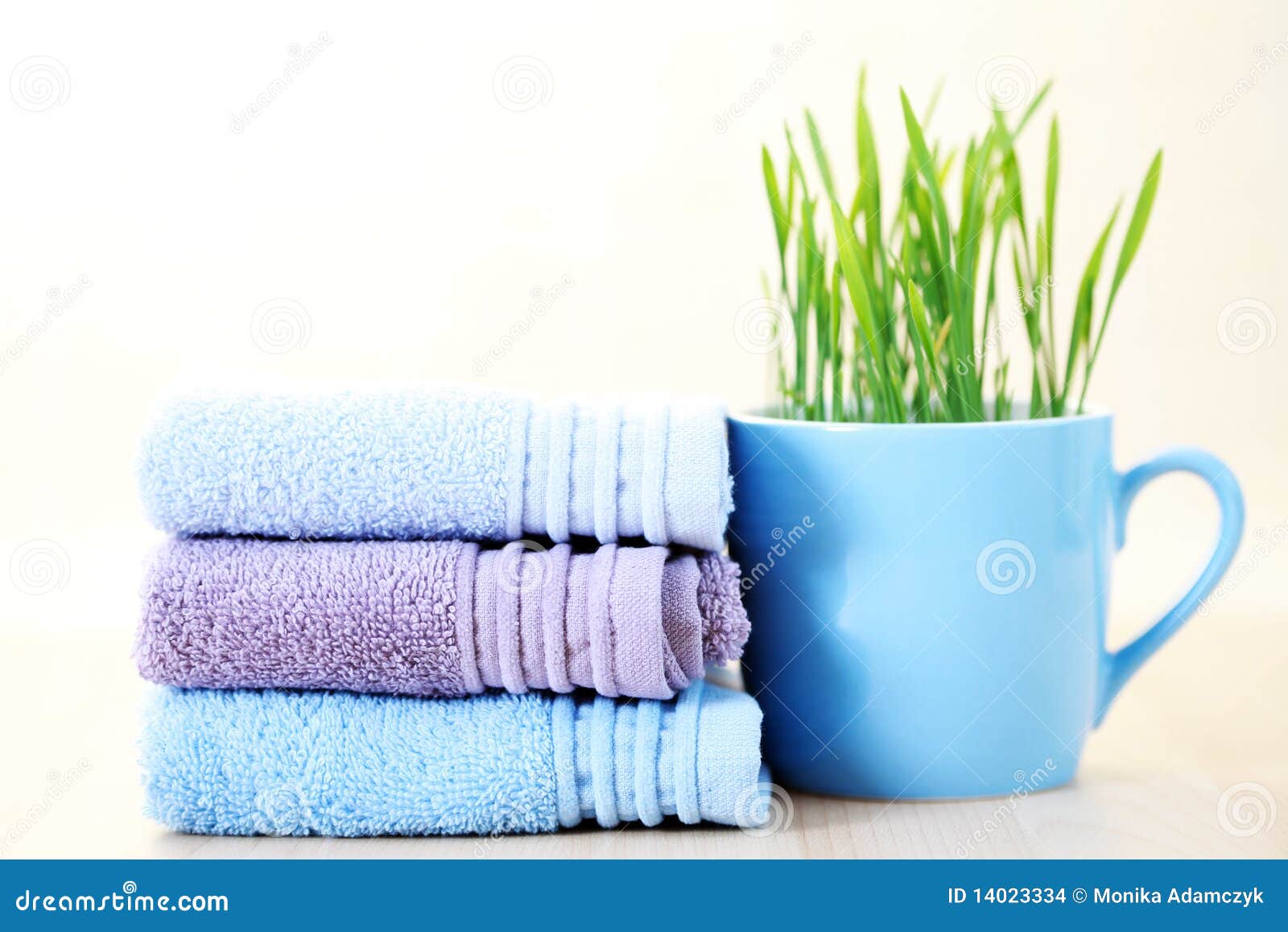 Stack of towels. Soft and fresh towels with cup of grass - beauty treatment