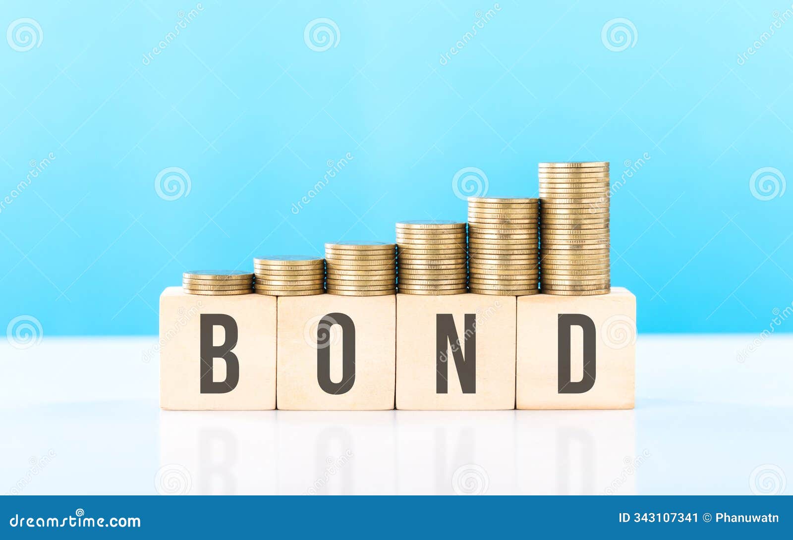 stack of various types coins alongside a wooden block labeled bond. steady and structured growth linked to bond investments,