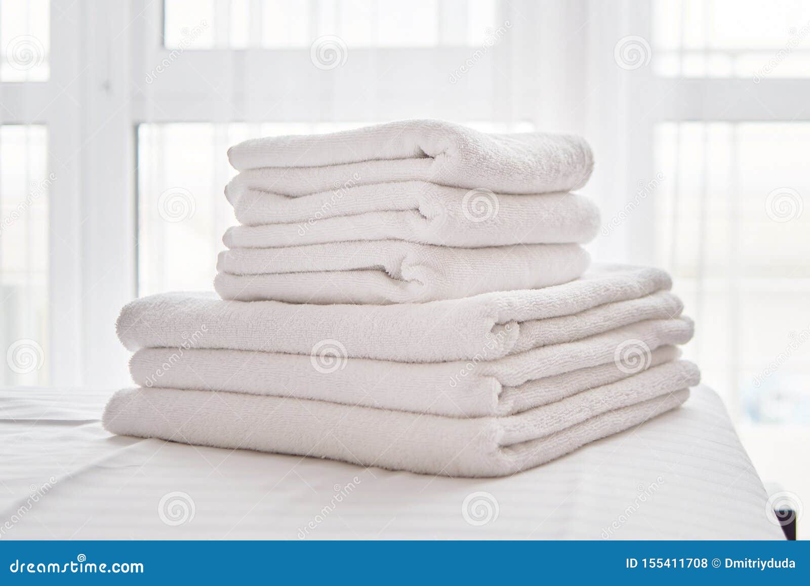 Stack of White Clean Bath Towels on Bed Sheet in Modern Bedroom