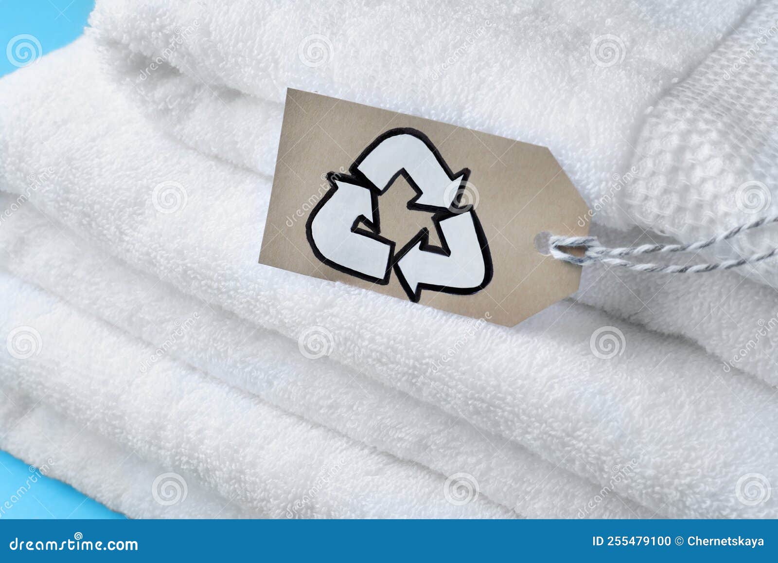 Stacked Towels with Recycling Label on Light Blue Background, Closeup