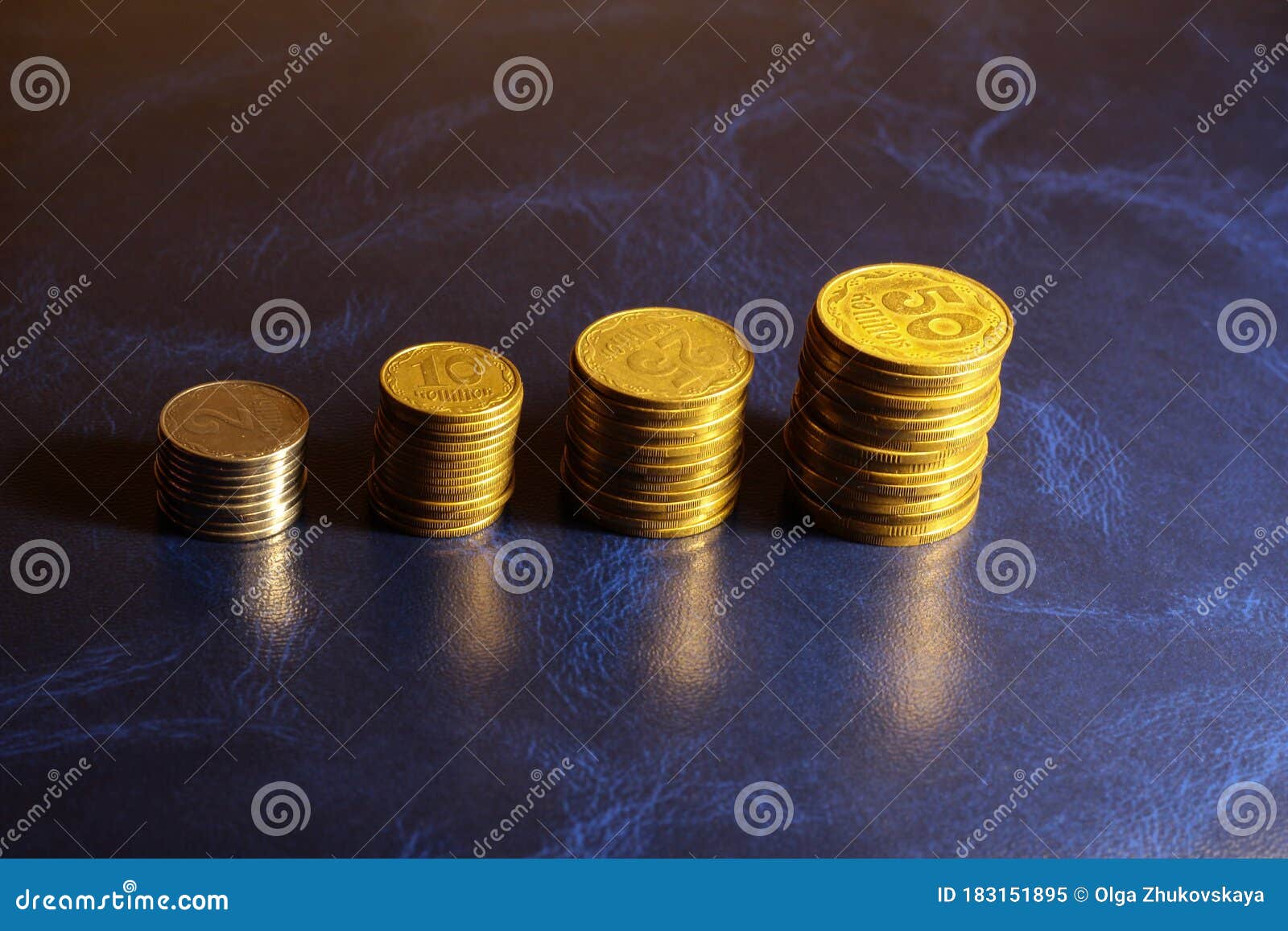 stacks of ukrainian coins on a blue background. 2, 10, 25, 50 ukrainian kopecks in stacks