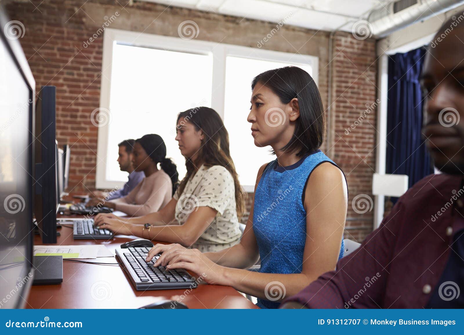 Staff Sitting at Desks Using Computers in Busy Office Stock Image