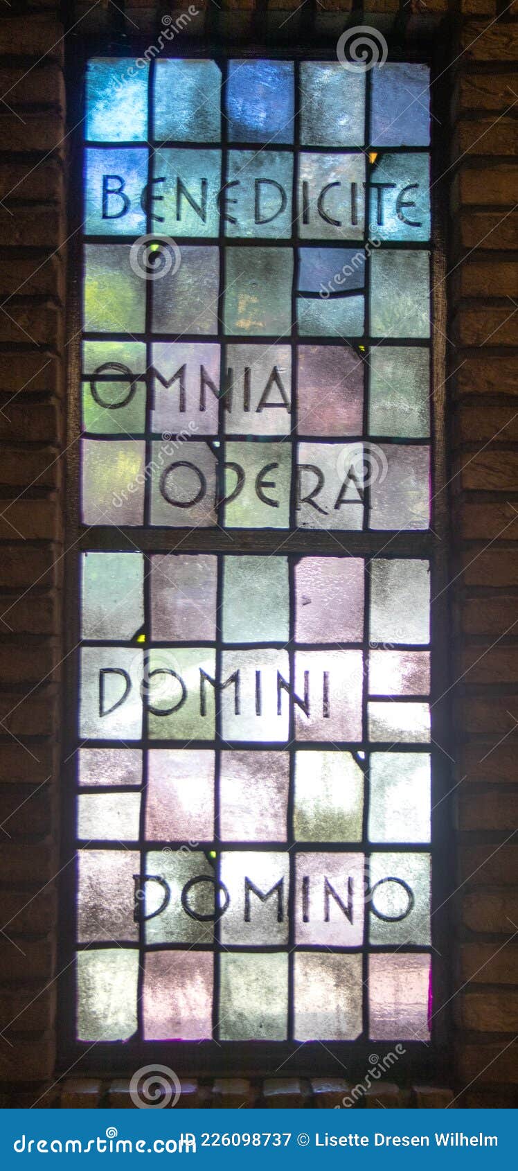 stained glass window with the text: benedicite omnia opera domini domino