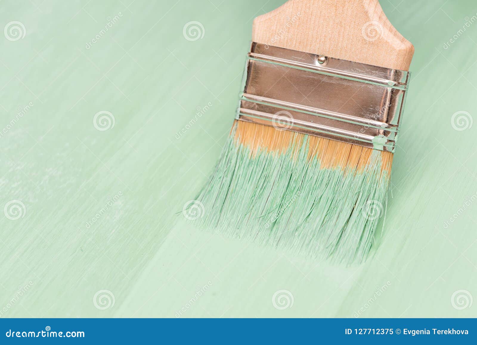 Staining Wood Surfaces with Green Paint Using a Paint Brush Stock Image