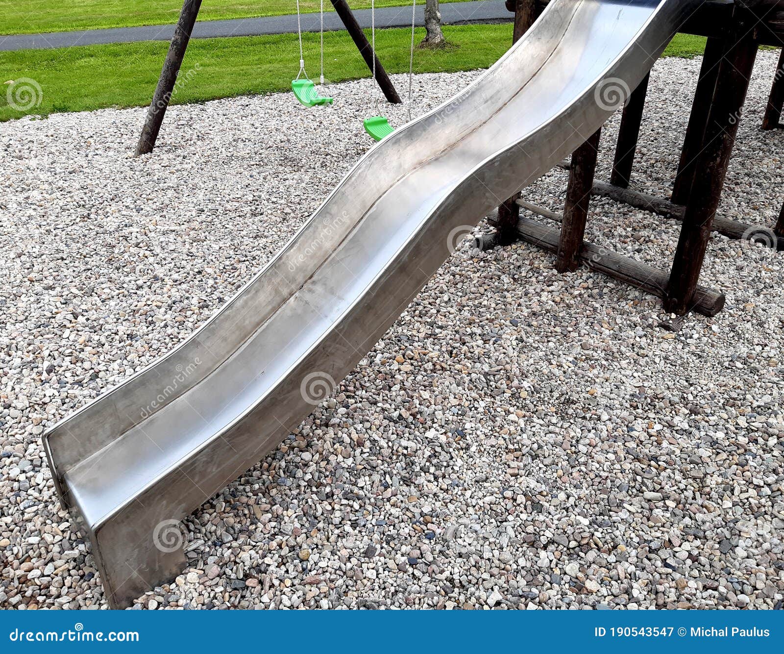 stainless steel slide and swings on the playground in the park in gray pebbles
