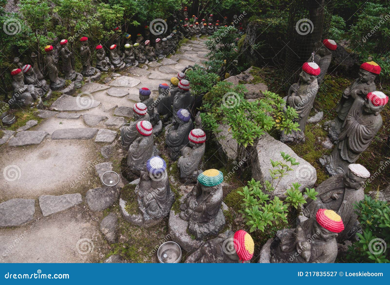 stairs surrounded by buddha statues with knitted hat offerings at the temple diasho-in in miyajima, hiroshima, japan