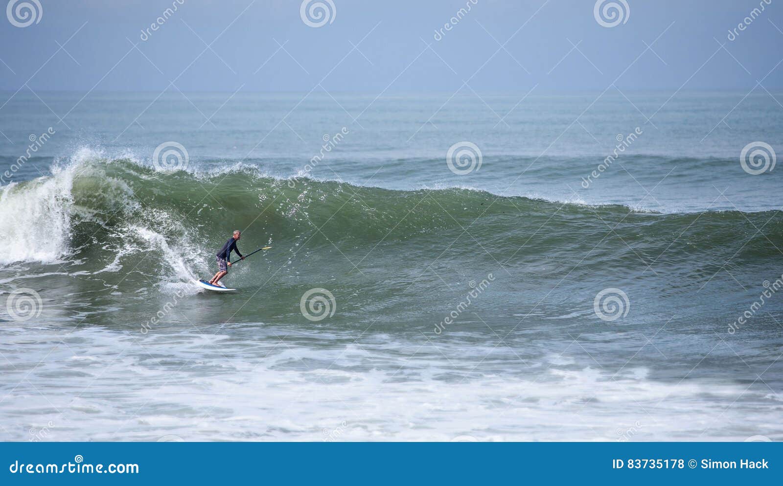 A Stand Up Paddle Boarder Surfing a Wave Editorial Stock Photo Image
