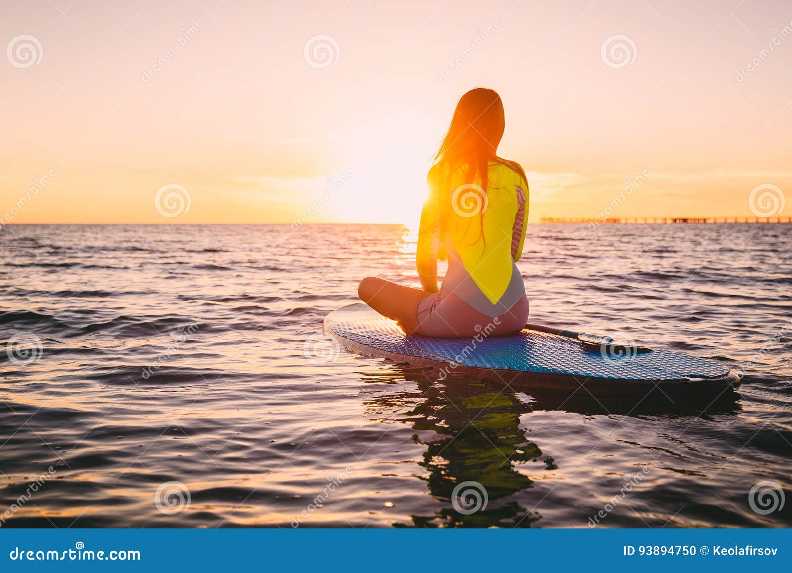 stand up paddle boarding on a quiet sea with warm summer sunset colors. relaxing on ocean